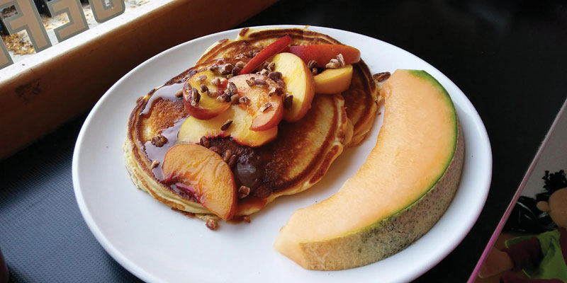 Pancakes with Michigan peaches in ginger syrup and caramel sauce and a wedge of cantaloupe