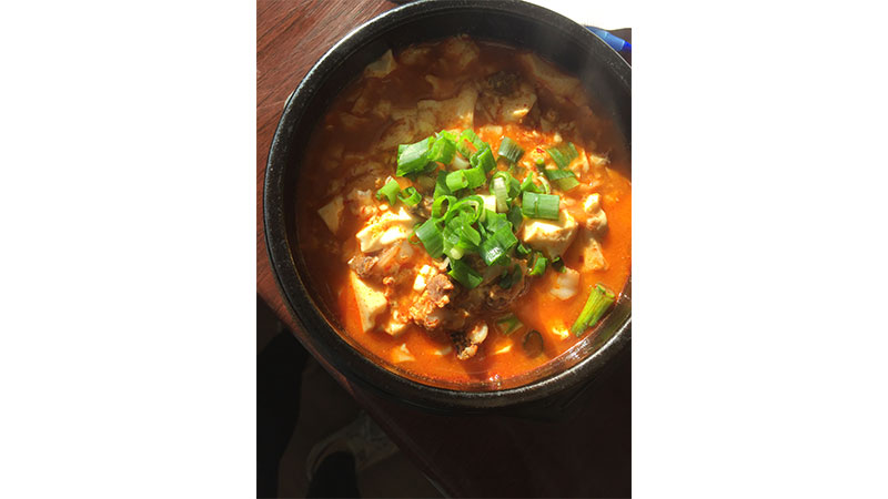 Soon Dooboo, a spicy tofu and seafood stew richly packed with tofu, shrimp, squid and mussels.