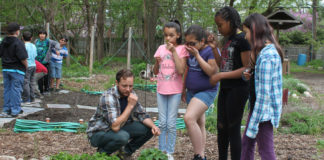Students from Mitchell Elementary smell fresh herbs in the garden with their teacher Mr. Popkey
