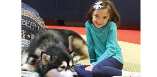 Kathryn, 8, pictured with service dog Hawkeye enjoying some reading time together during the READ program.