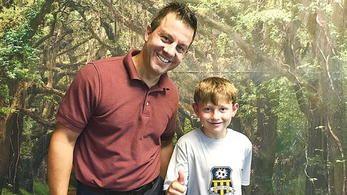 Dr. Mark Bowers and one of his patients, Connor, 9, pose in front of the forest wall at the Brighton Center for Pediatric Neurodevelopment. Photo contributed by Miranda Keskes.