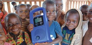 Children in Cameroon hold a crank-powered mp3 player used to deliver preschool lessons to them through the Two Rabbits nonprofit organization. Ann Arbor native Sarah Strader started the organization to help the Baka children of Cameroon find success in a formal classroom setting and their forest home. Photo contributed by Sarah Strader