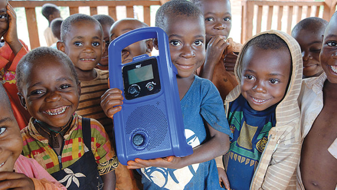 Children in Cameroon hold a crank-powered mp3 player used to deliver preschool lessons to them through the Two Rabbits nonprofit organization. Ann Arbor native Sarah Strader started the organization to help the Baka children of Cameroon find success in a formal classroom setting and their forest home. Photo contributed by Sarah Strader