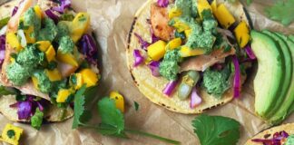 A sheet tray with corn torillas topped with fish, slaw and mango salsa
