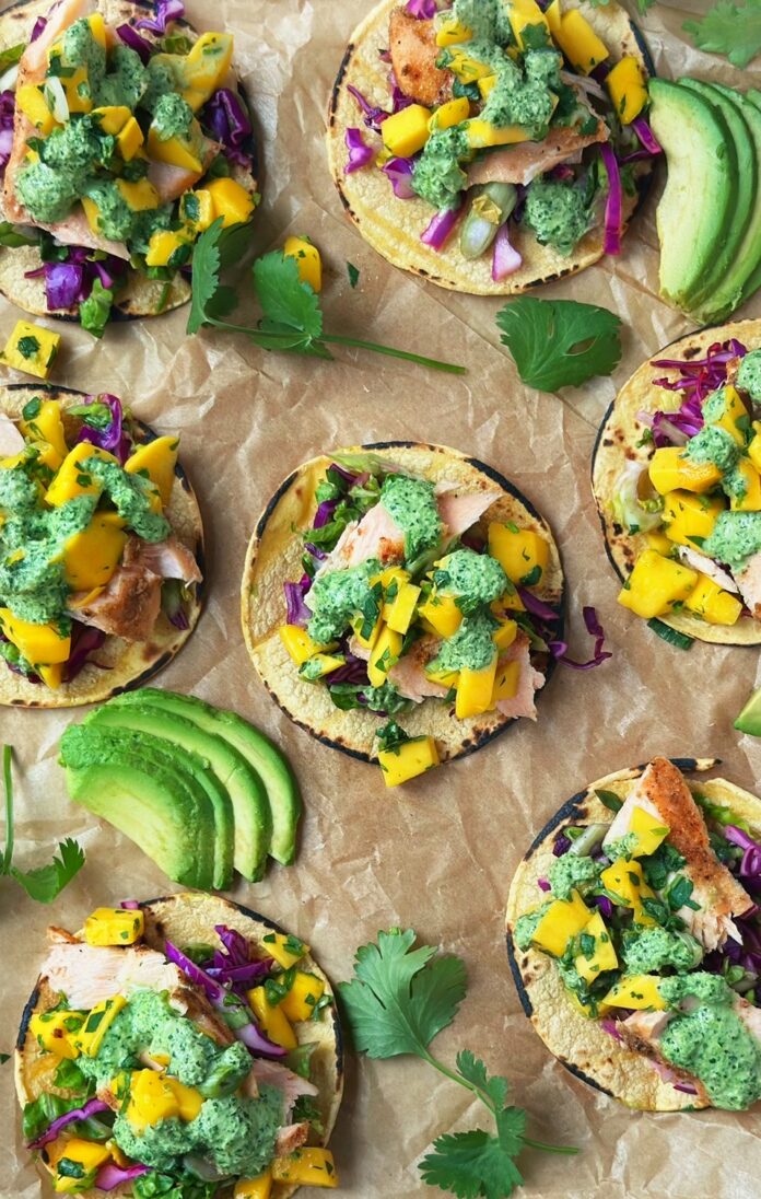 A sheet tray with corn torillas topped with fish, slaw and mango salsa