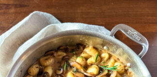 A large saute pan with gnocchi and mushrooms inside.