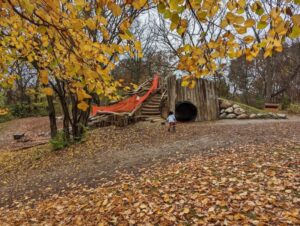 A kid playing near a wooden fort.