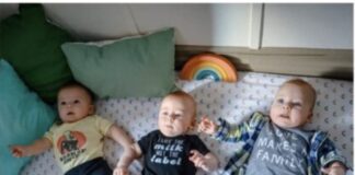 Three children laying on a bed.