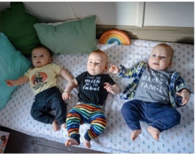 Three children laying on a bed.