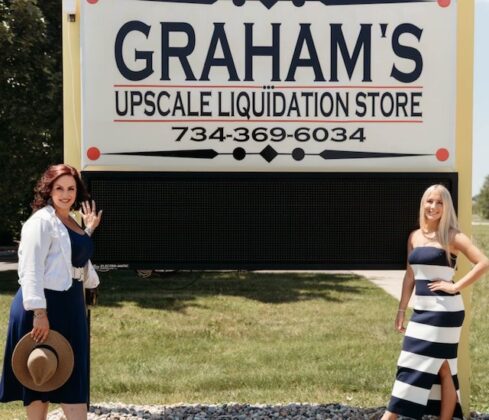 Two people standing by a sign.