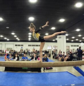 A child on a balance beam in a gymnastics class.