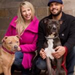 A couple taking a picture with their dogs.