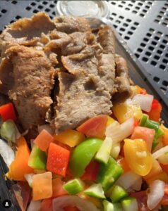 Close-up of gyro meat and chopped, fresh looking vegetables like peppers and onion.
