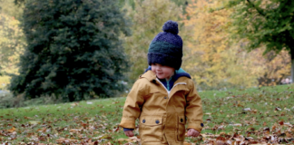Boy in coat and hat walking in leaves