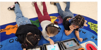 Three students laying on their stomach working on laptops