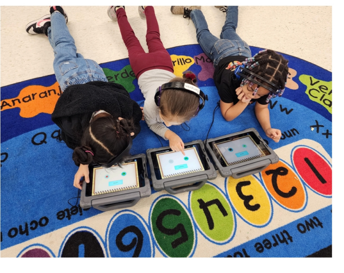 Three students laying on their stomach working on laptops