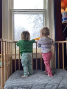 Twins watching snow fall outside window
