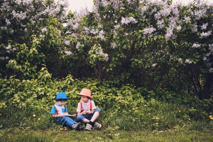 Photo of 2 kids reading under a tree