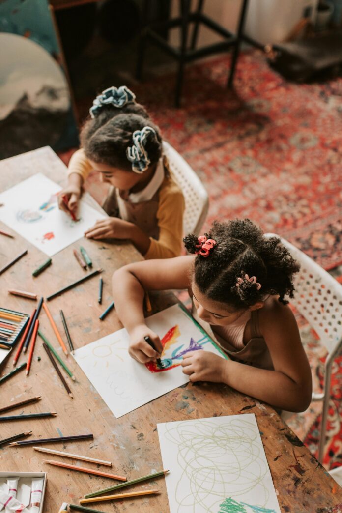 Two young girls coloring at table