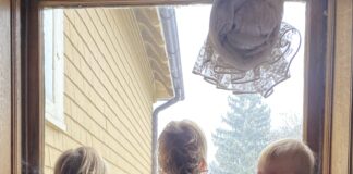 Triplets looking at window with one looking at camera