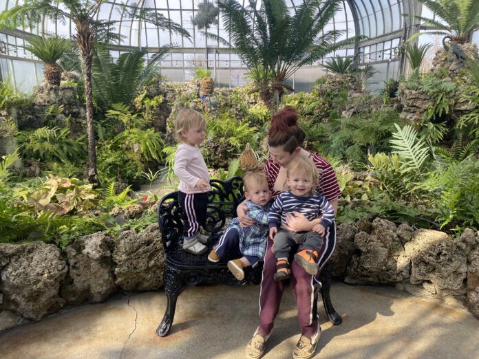 Triplets with mother in area with plants