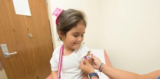 young girl getting bandaid put on her in doctor's office.