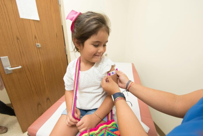 young girl getting bandaid put on her in doctor's office.