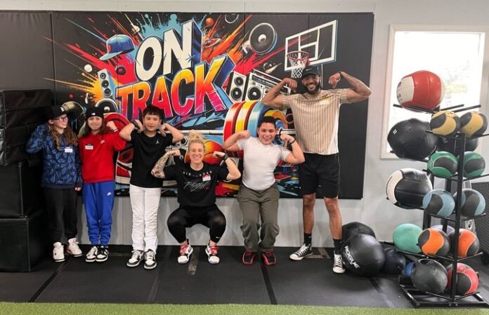 Adults and youth standing in front of a colorful banner that says 