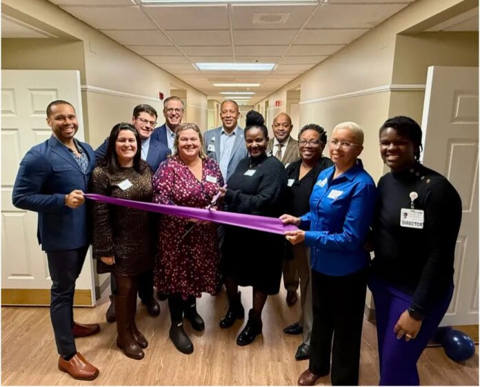 Group of racially diverse people in a hallway with an African American woman in a black dress holding the ceremonial 