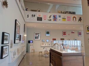 A large room with views up to the second floor. The walls are covered in framed paintings.