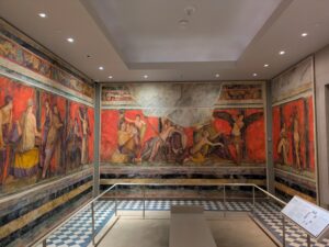 A small room covered in murals that appear to be roman. 